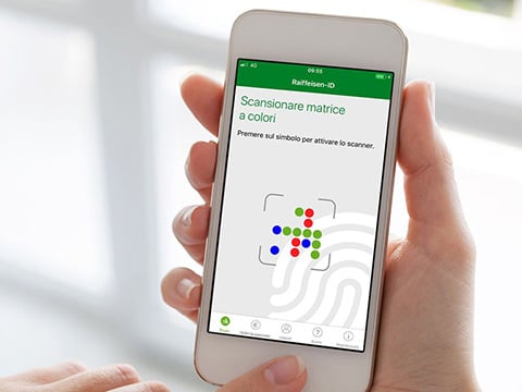 A hand, against a light background, holding a mobile device with a colorful QR code on screen