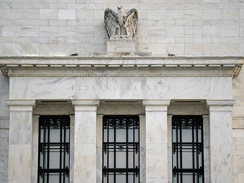 The columned, marble facade of a bank with an sculpted eagle resting on top of its overhang
