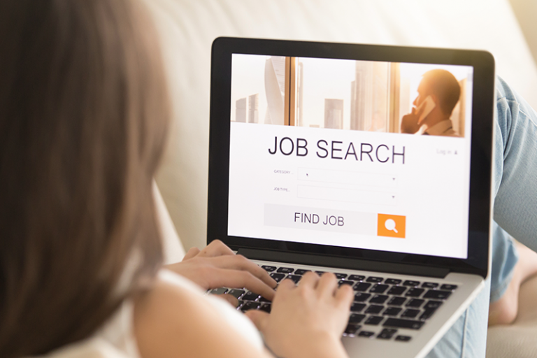 5 Tips to Protect Your Privacy Online During a Job Hunt - Over-the-shoulder view of a woman sitting with a laptop on her lap, with "Job search" on the header of a web page and "Find job" within a search bar in the bottom third of the screen