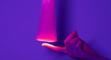 Hand touching red optical fiber 